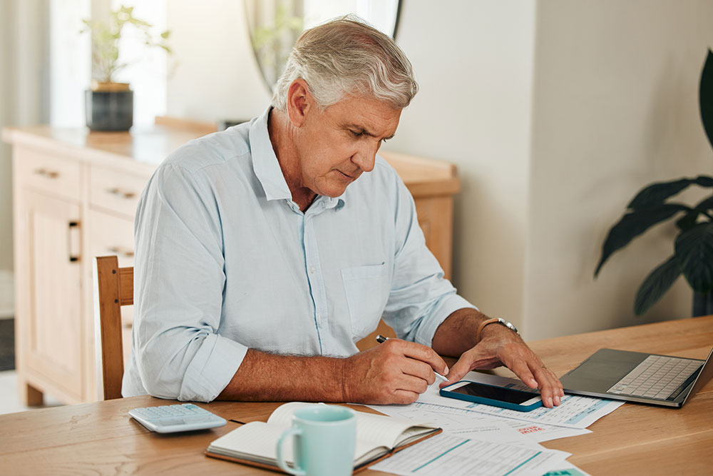 Senior man at table looking at cataract surgery costs.