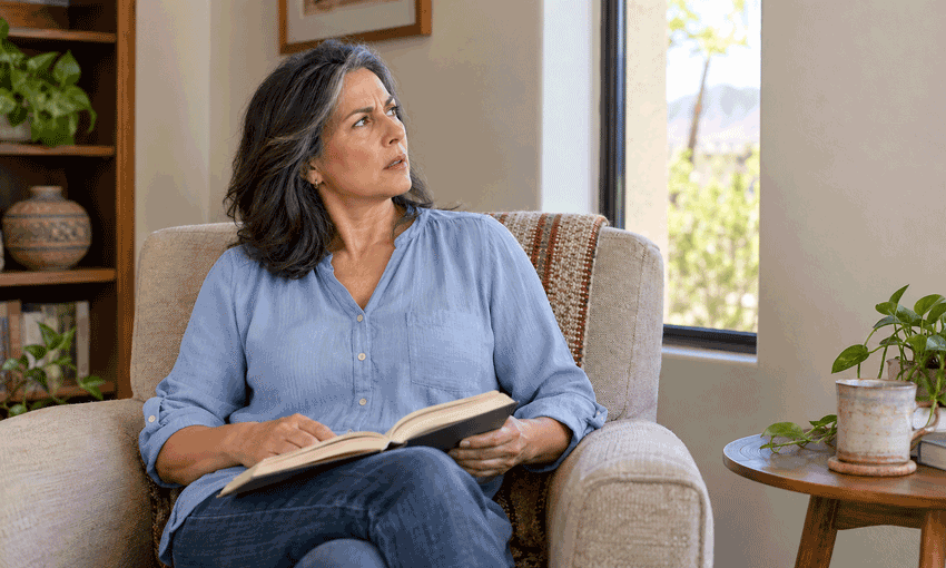 Woman in a soft blue blouse pauses reading and looks up with concern, accompanying M&M Eye Institute’s guide to floaters and flashes in your vision.