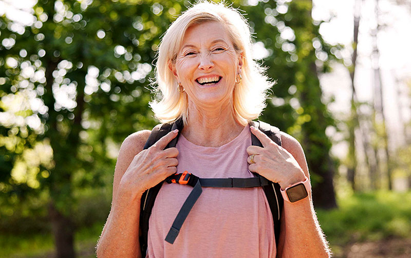 Is Glaucoma Hereditary? Happy mature woman with backpack enjoying outdoors to illustrate genetic and lifestyle risk factors for glaucoma