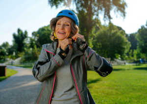 Is Glaucoma Hereditary? A mature woman putting on a bike helmet and wrist guards to symbolize managing modifiable risk factors for glaucoma