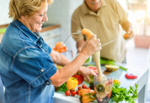 A smiling senior couple preparing a healthy meal together in their kitchen, illustrating lifestyle adjustments after a glaucoma diagnosis